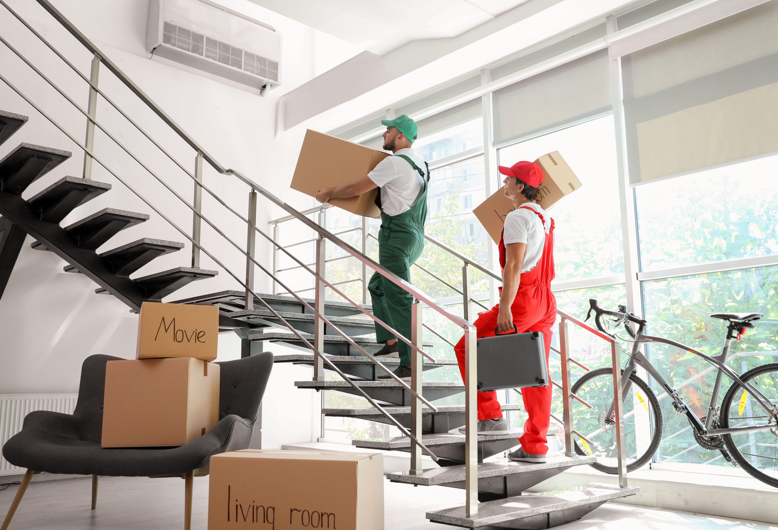 Umzugshelfer tragen Kartons die Treppe hoch.