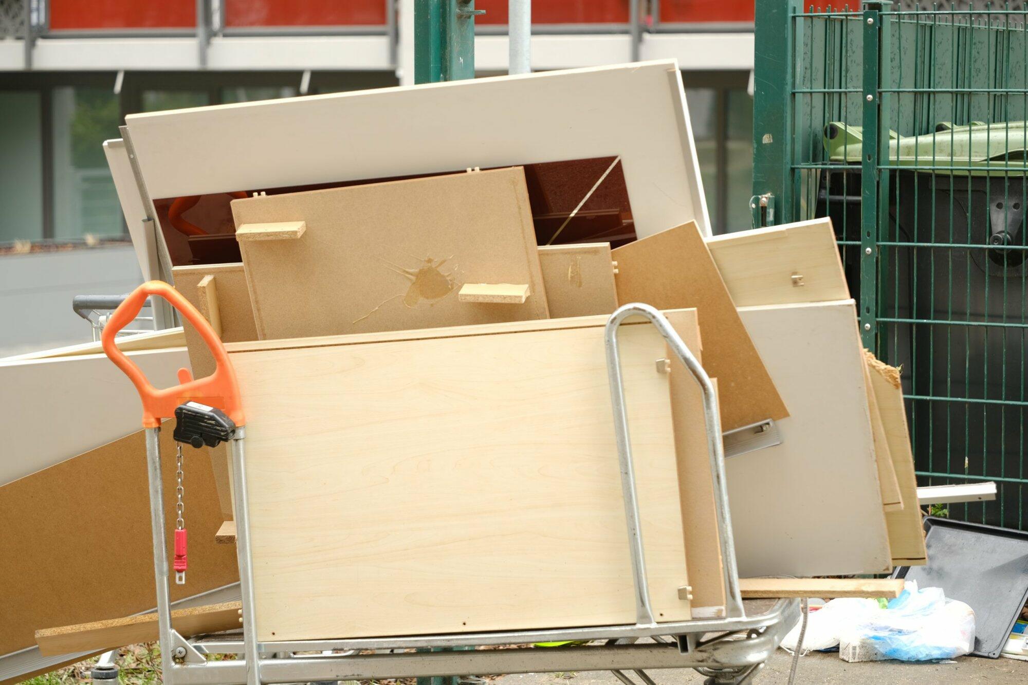 Ausrangierte Möbelteile neben Müllcontainer im Freien